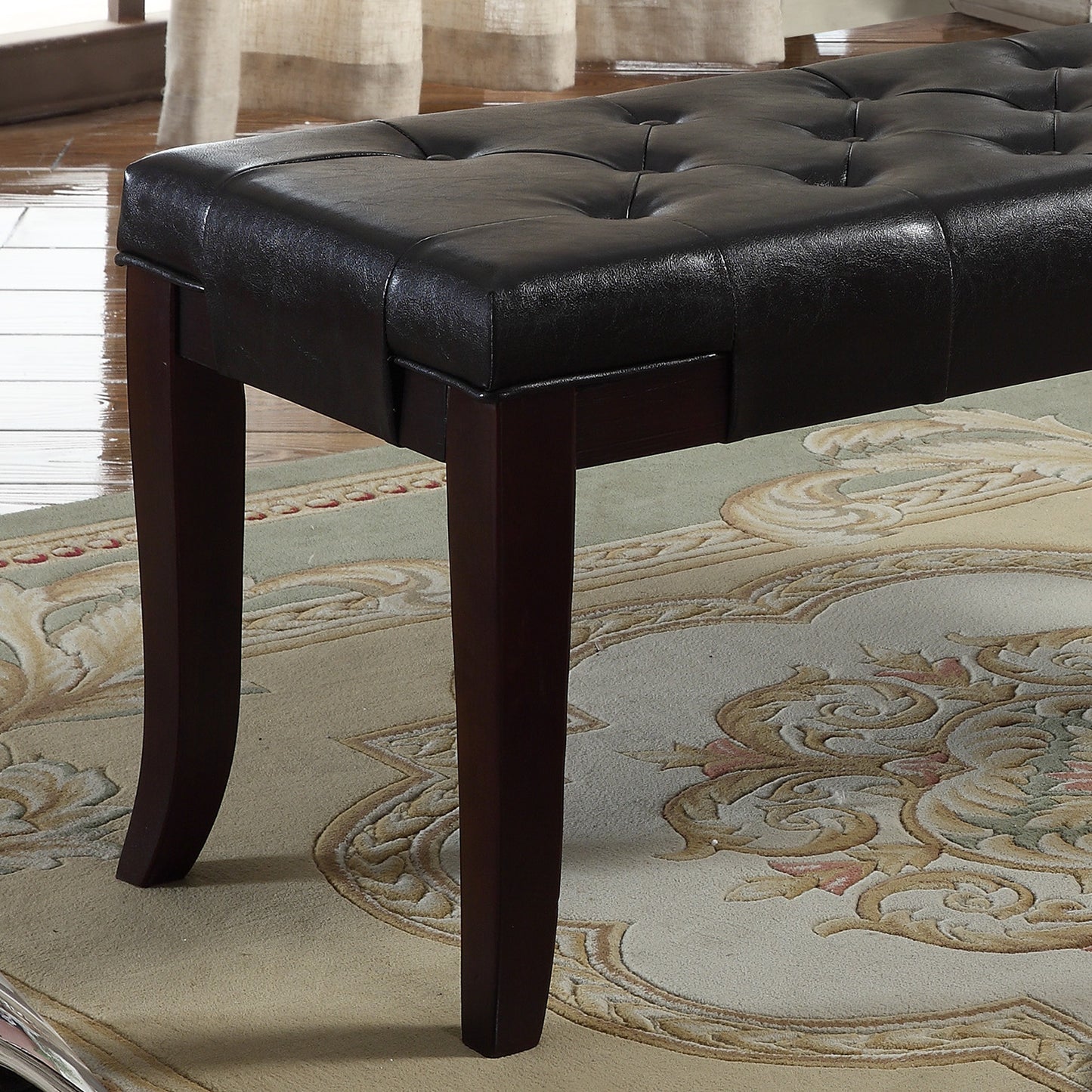 Dark brown tufted leather bench with espresso wood legs on an ornate rug