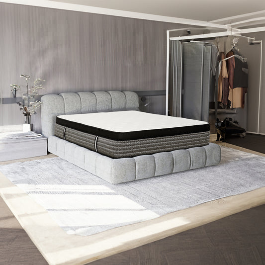 Plush gray upholstered bed frame with a white and black patterned hybrid mattress