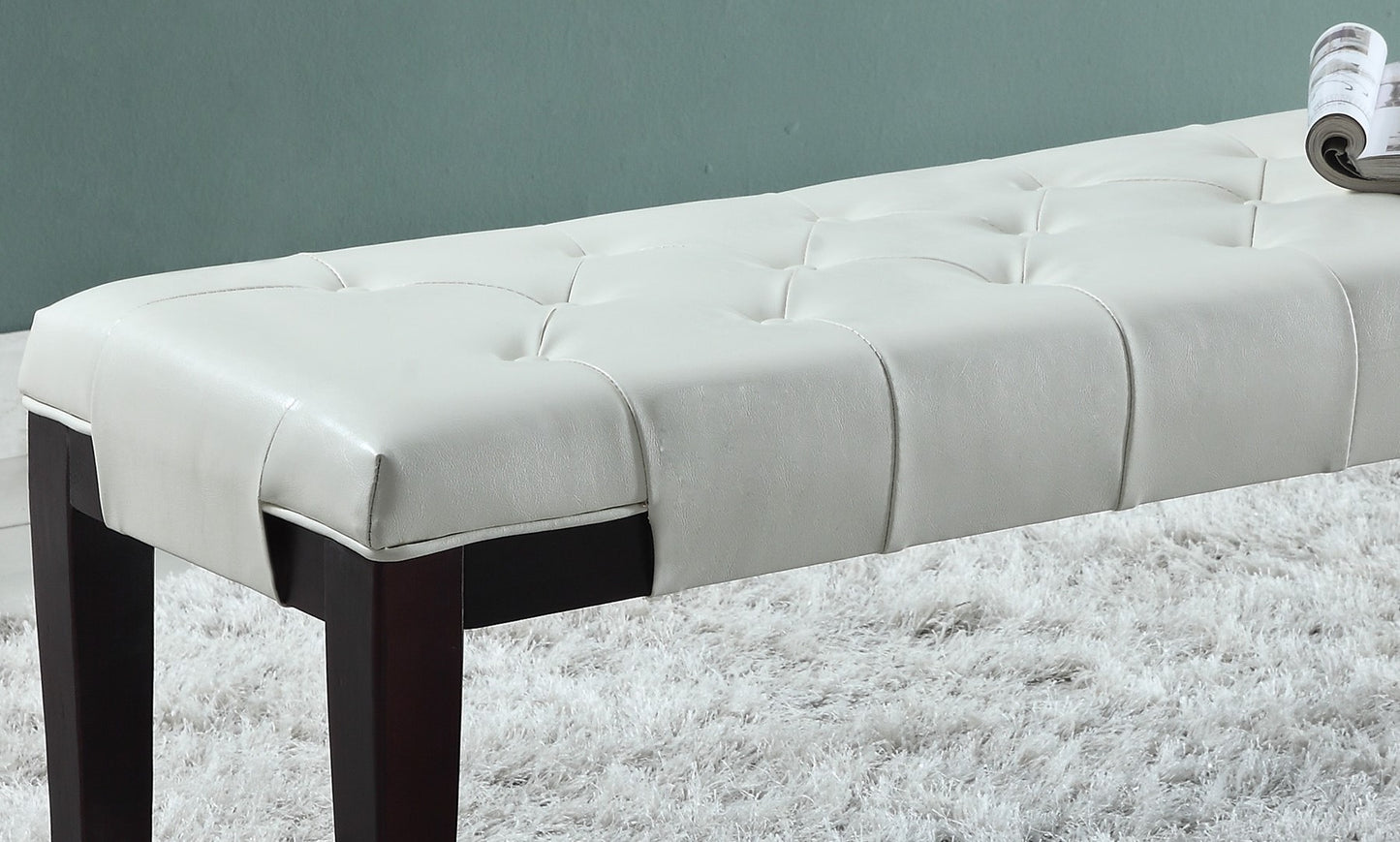 White faux leather tufted bench with dark wood legs on fluffy rug