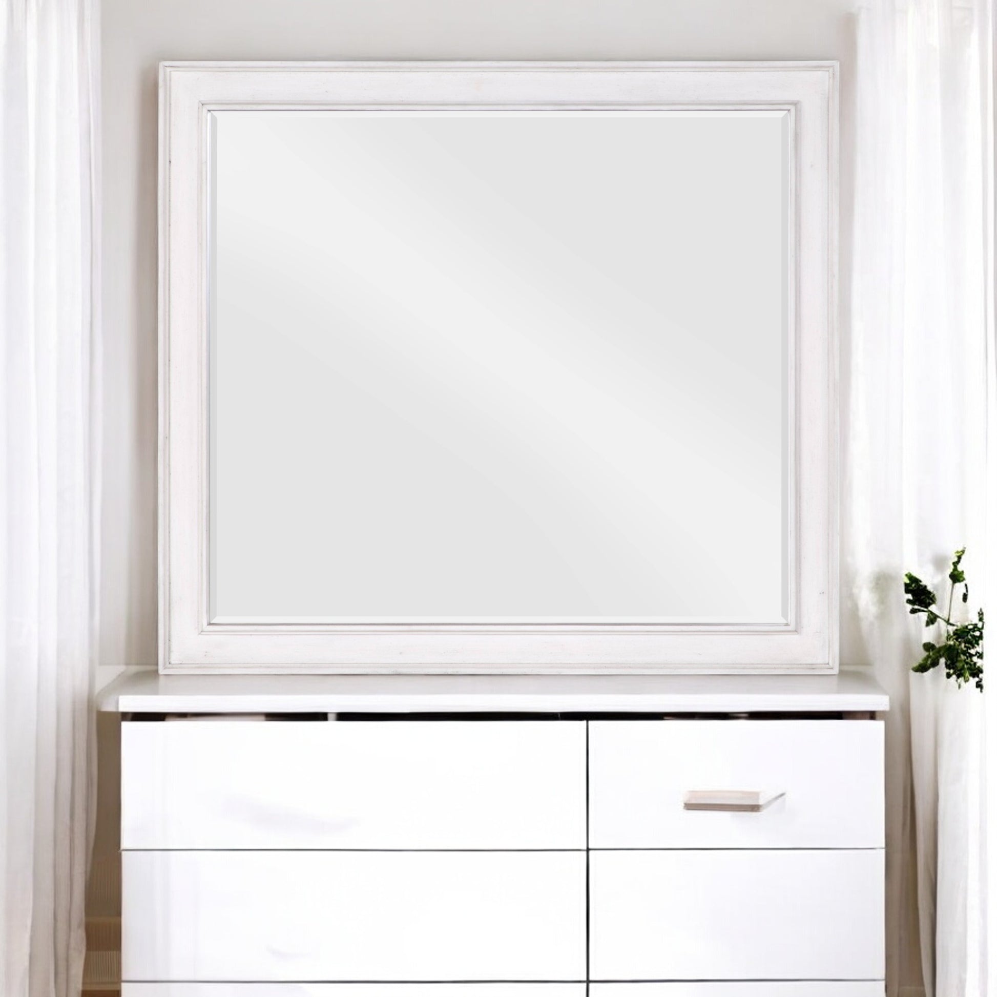 White distressed wood framed rectangular wall mirror over a white dresser