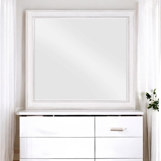 White distressed wood framed rectangular wall mirror over a white dresser