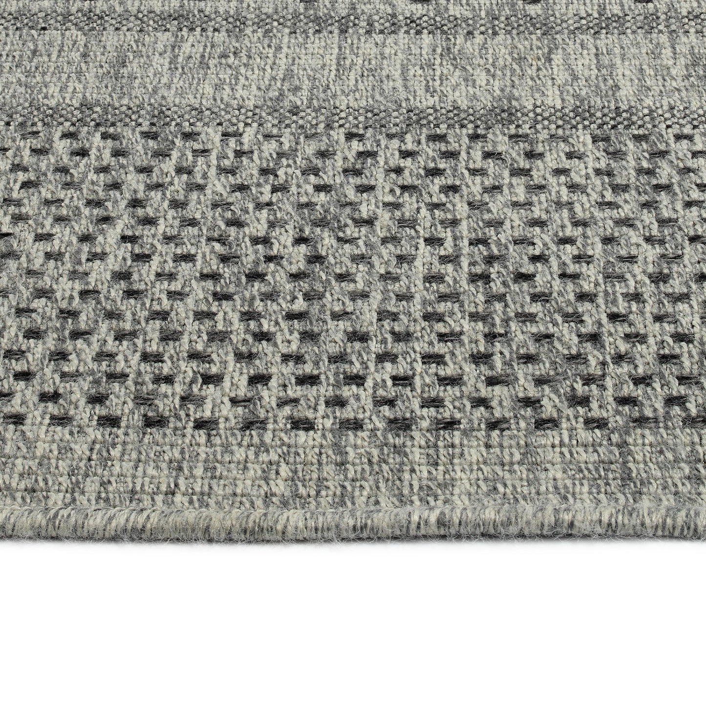 Closeup of a textured grey and cream patterned area rug with a woven design