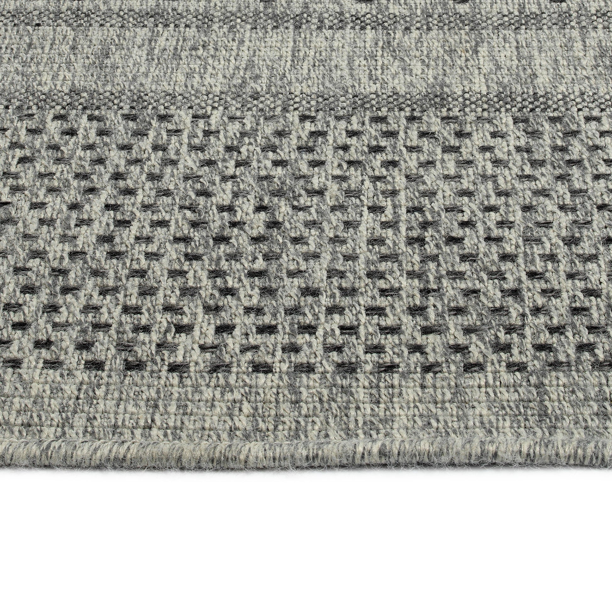 Closeup of a textured grey and cream patterned area rug with a woven design