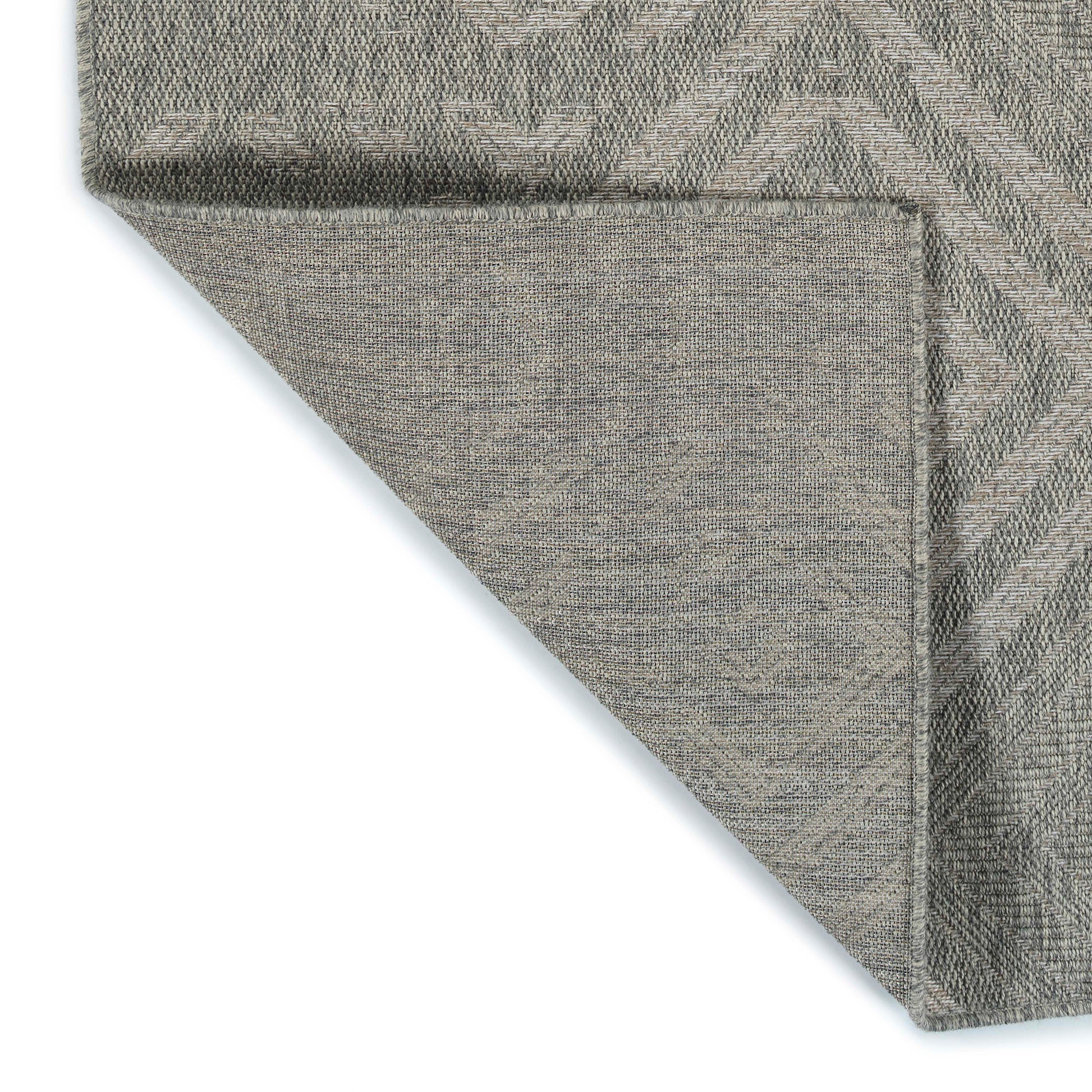 Closeup of a grey textured rug with a subtle chevron pattern showcasing its woven fabric construction
