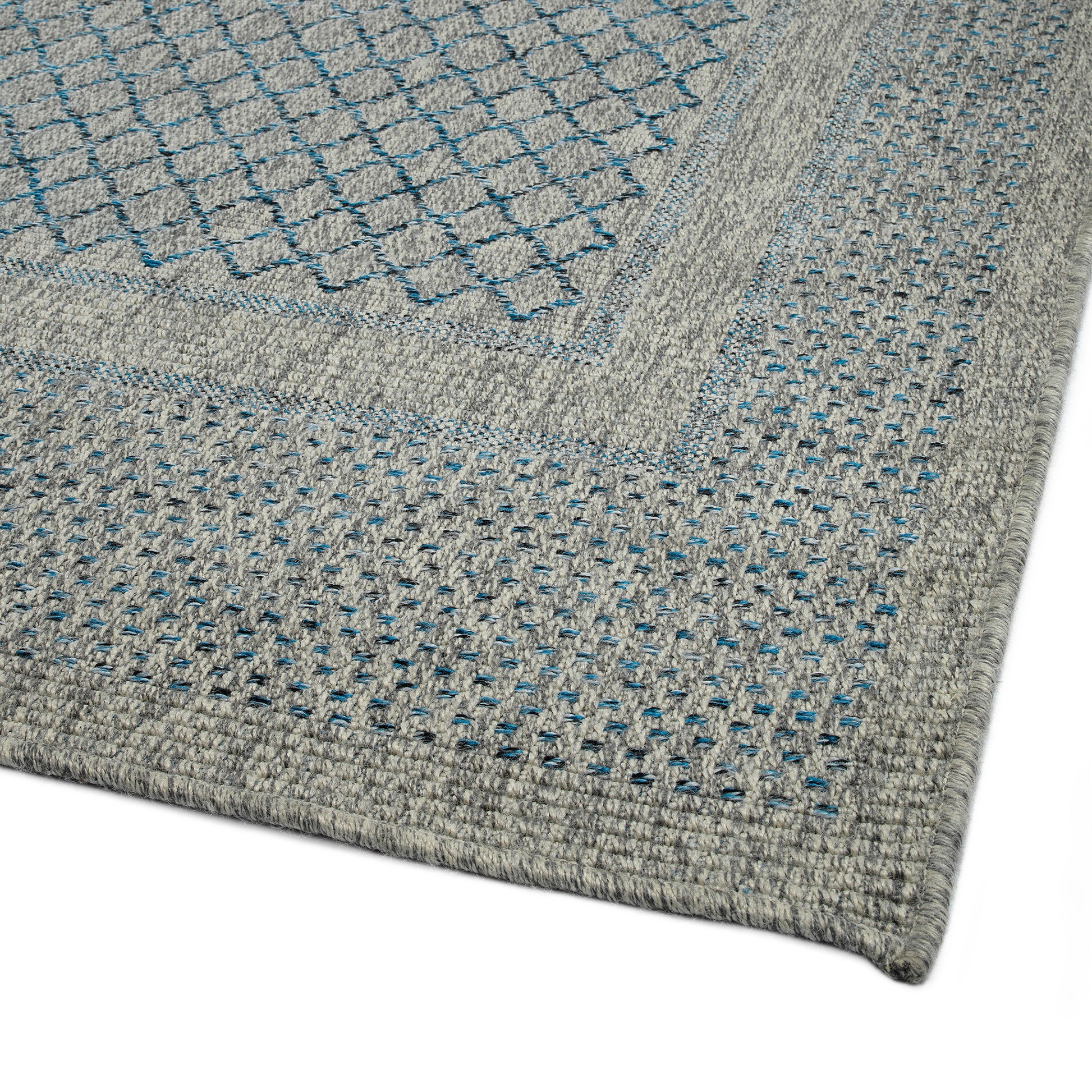 Closeup of a grey braided rug with a diamond pattern in blue and black accents