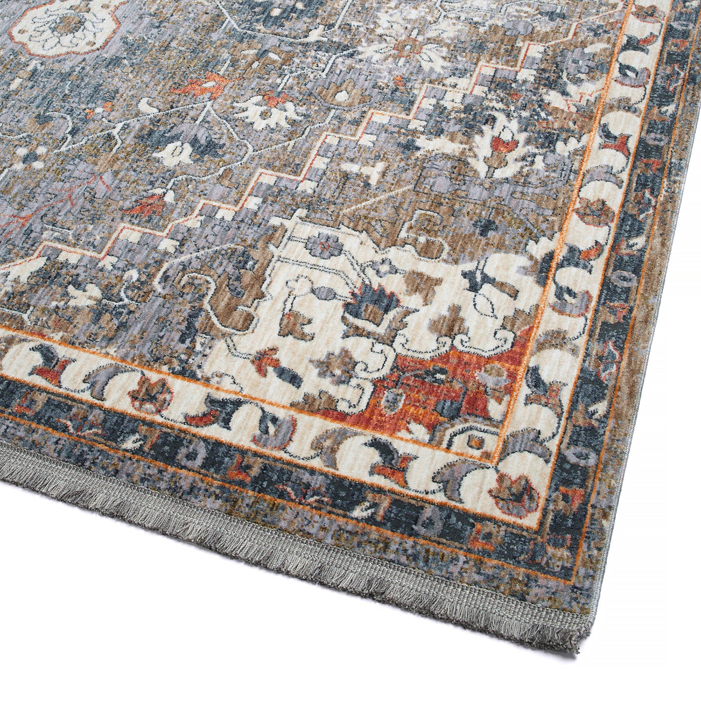 Closeup of a distressed Persian rug in grey cream and burnt orange with fringed edges