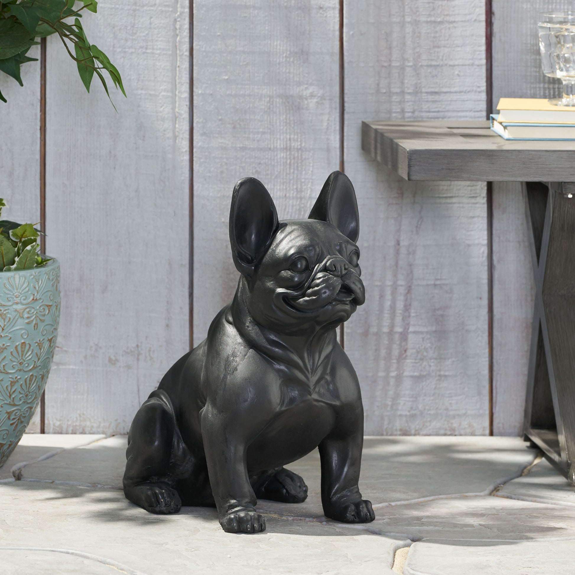 Black French Bulldog garden statue with large ears sitting attentively outdoors