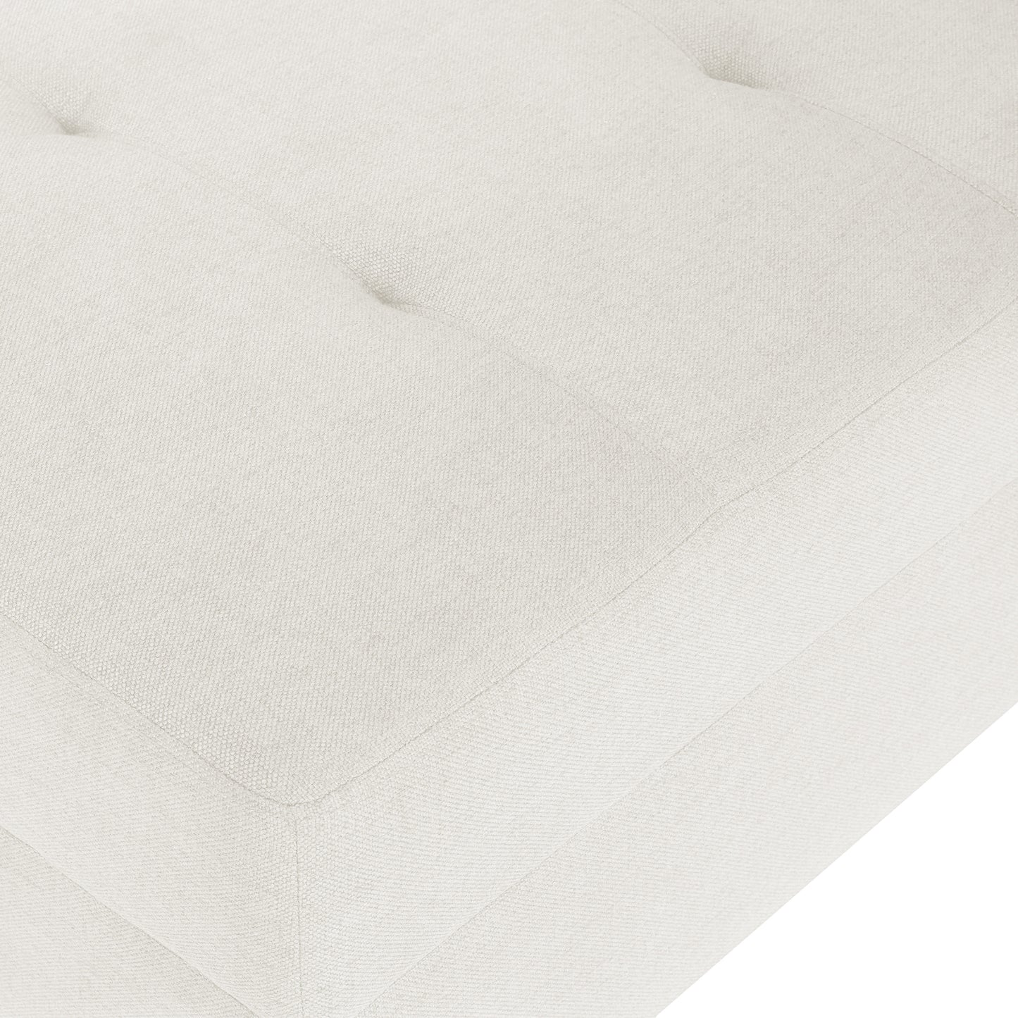 Closeup of a creamcolored linen tufted ottoman showing textured fabric and stitching detail