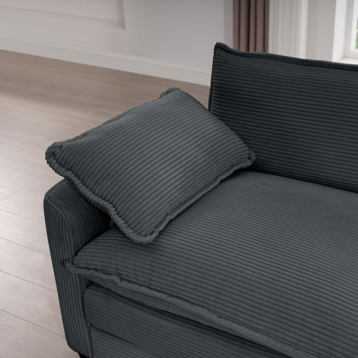 Closeup of a dark gray corduroy sofa with textured fabric and a matching throw pillow