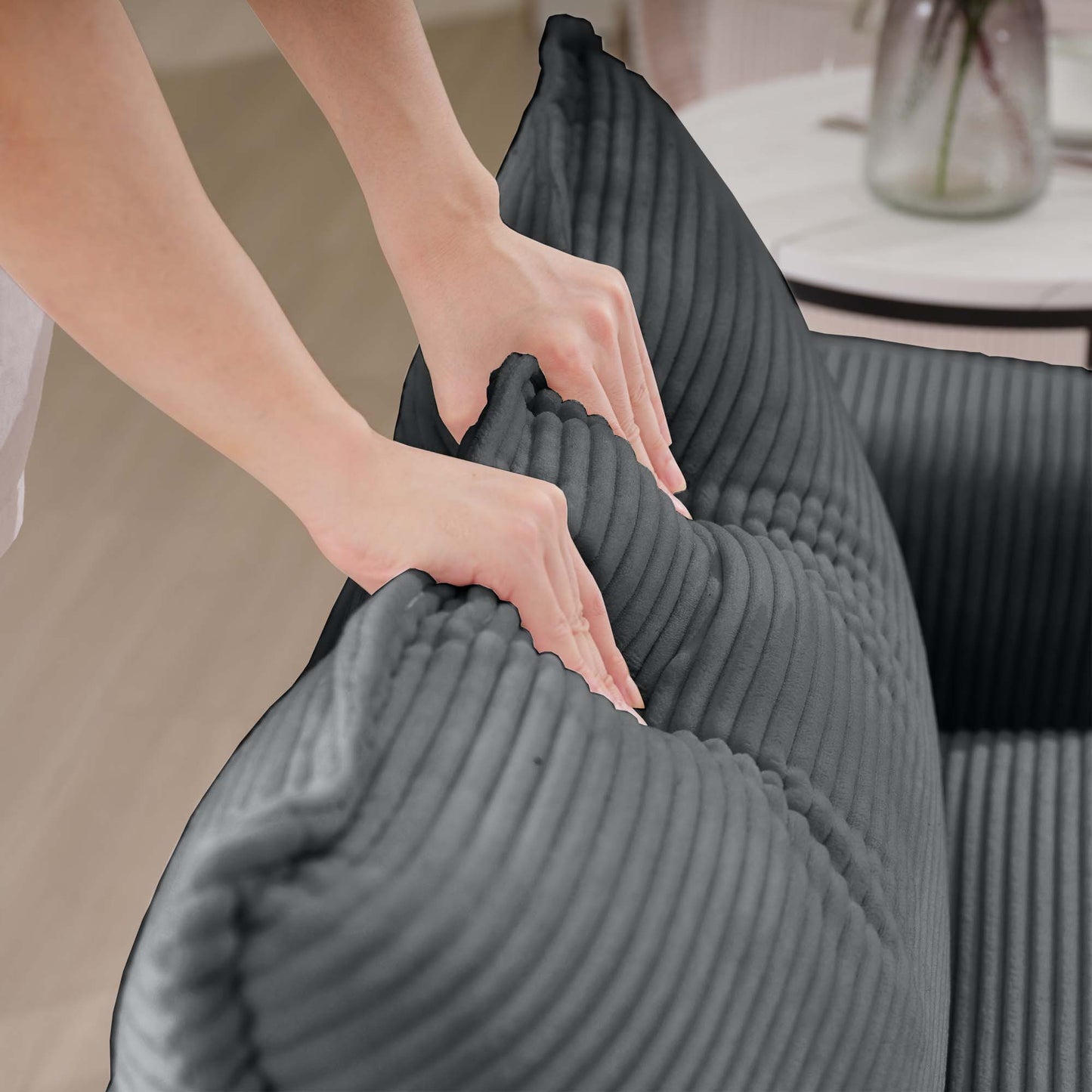 Hands adjust plush dark grey corduroy bean bag chair for cozy seating