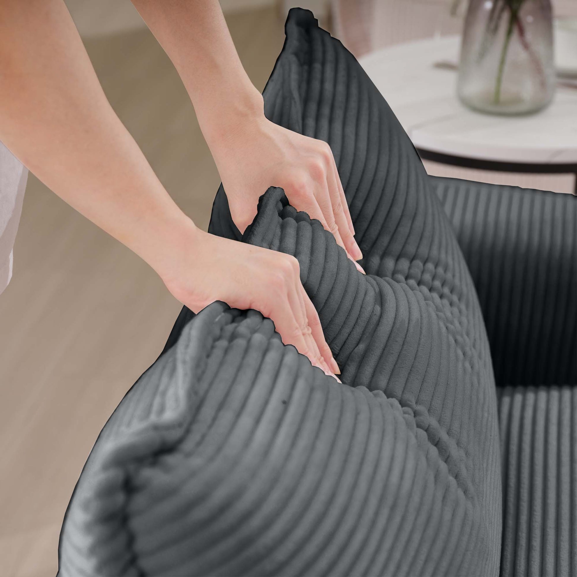 Hands adjust plush dark grey corduroy bean bag chair for cozy seating