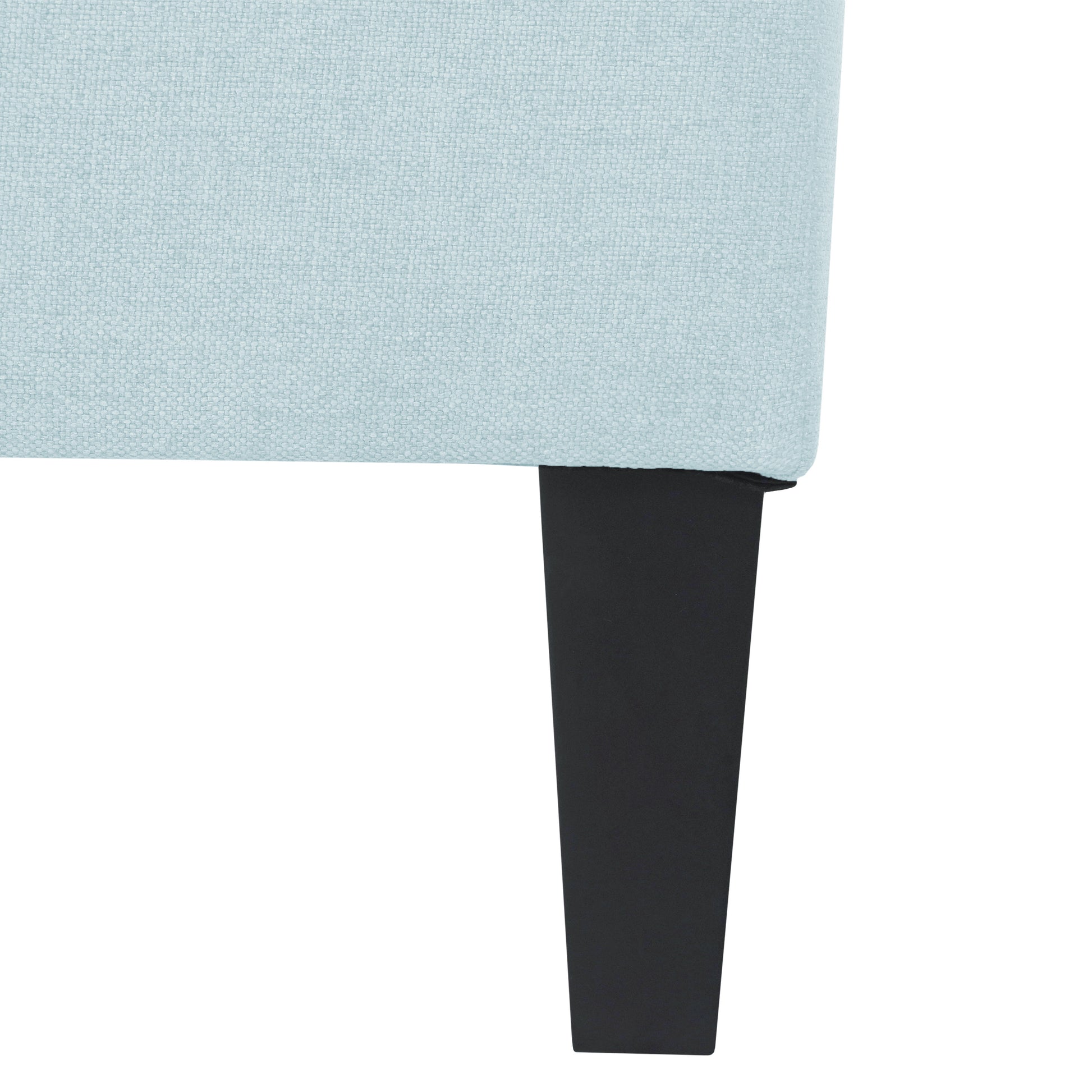 Closeup of a pale blue textured fabric sofa armrest with a black tapered leg