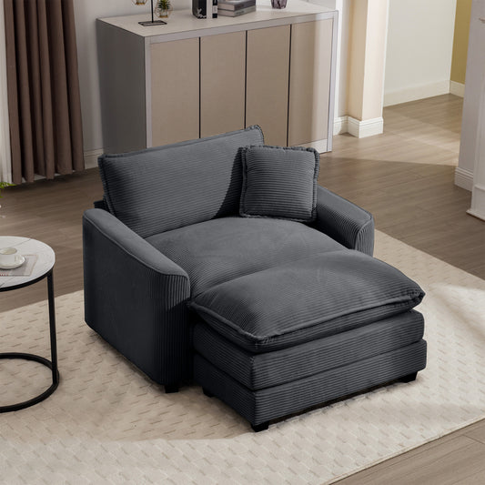 Dark grey corduroy armchair with ottoman and matching pillow for comfortable seating