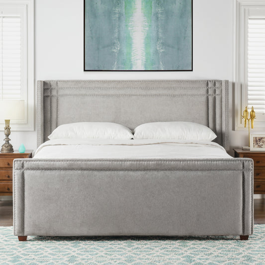 Grey upholstered bed with wingback headboard and silver nailhead trim