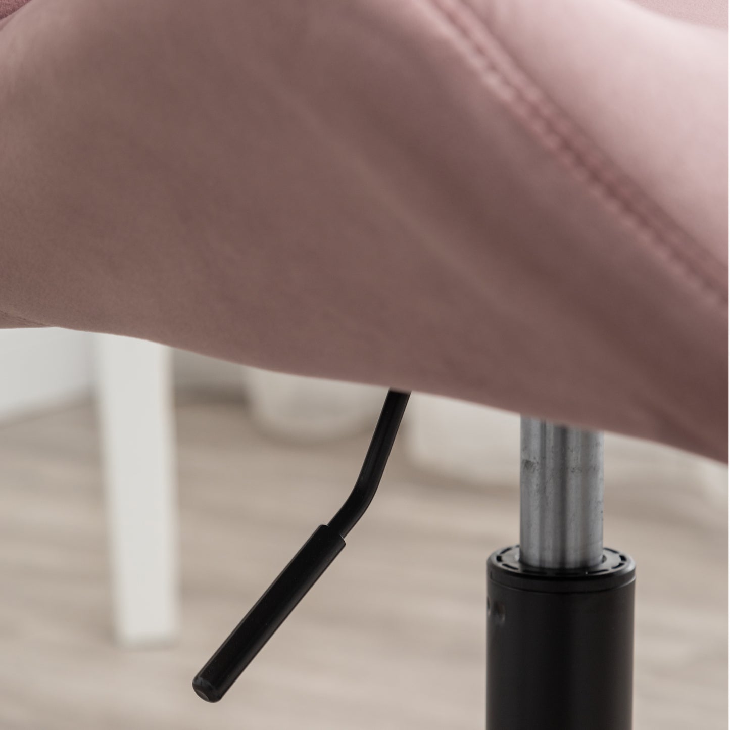 Closeup of pink velvet accent chair mechanism with height adjustment lever