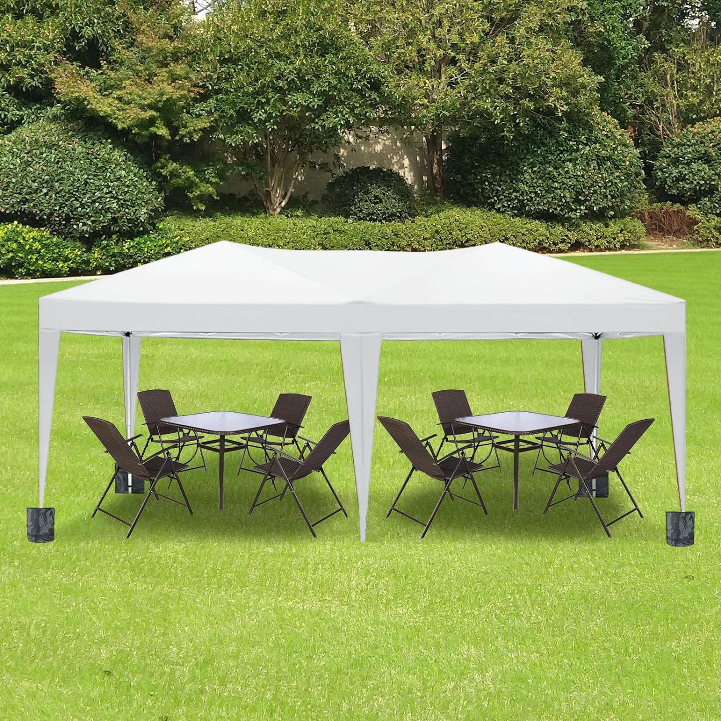 White outdoor canopy tent set up with two patio table and chair sets on green grass