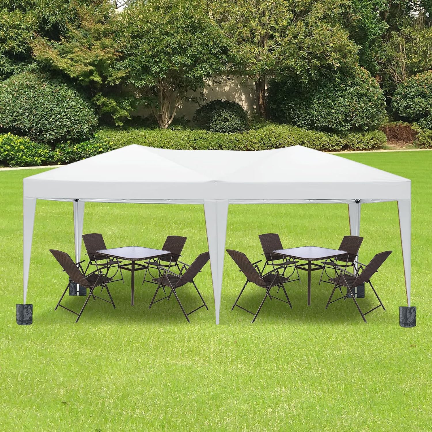 White outdoor canopy tent set up with two patio table and chair sets on green grass