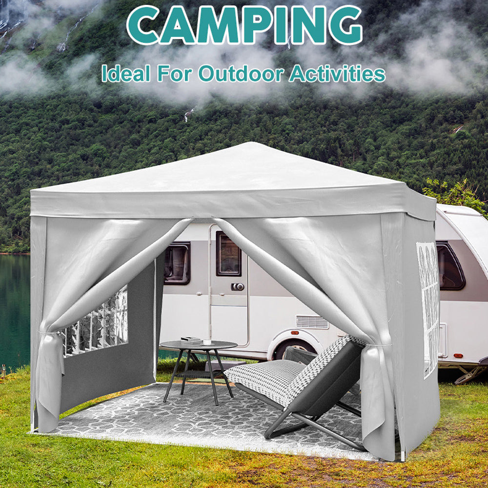 Gray canopy tent set up for camping next to a recreational vehicle on a grassy area