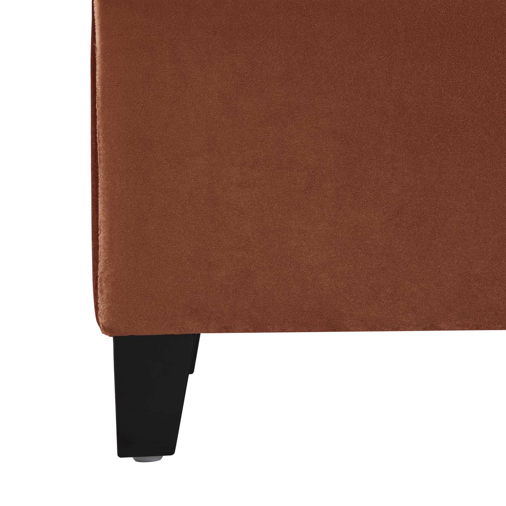 Closeup of a rich copper velvet sofa corner with black legs soft texture