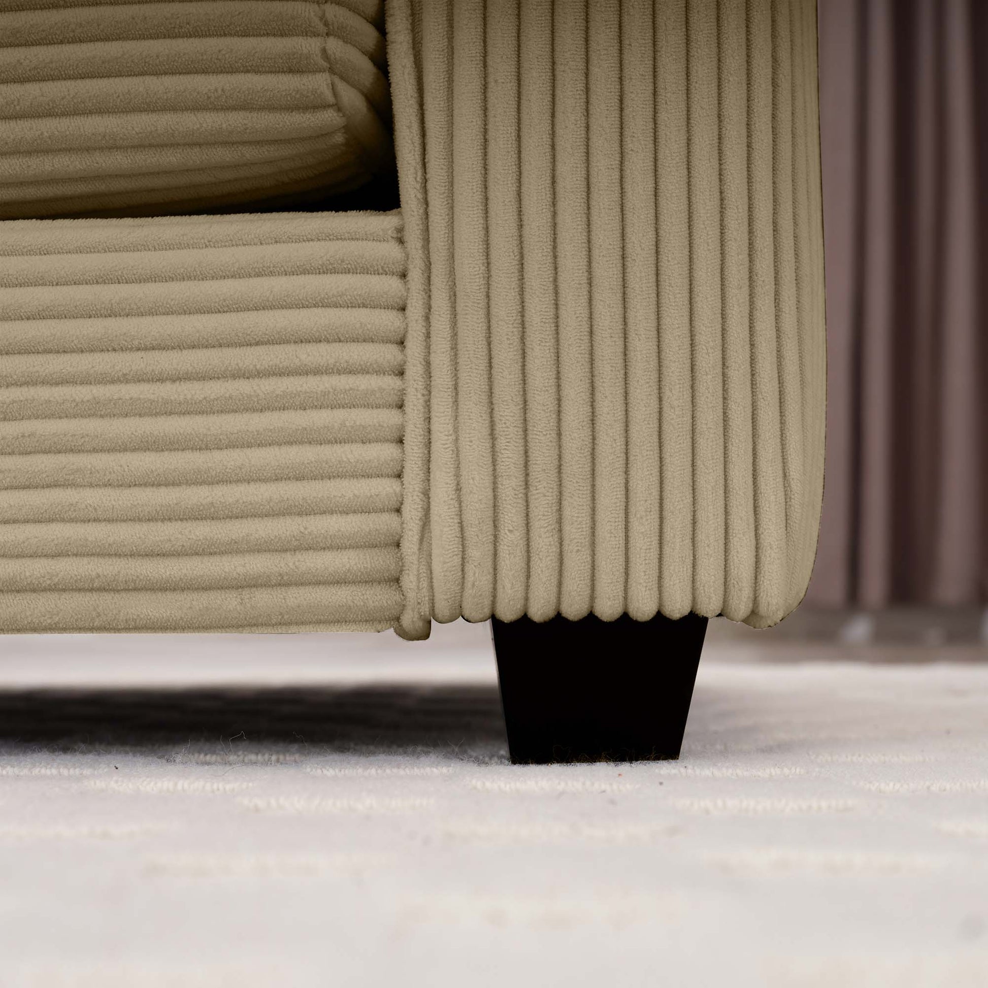 Beige corduroy armchair detail showing plush vertical ridges and dark wooden leg