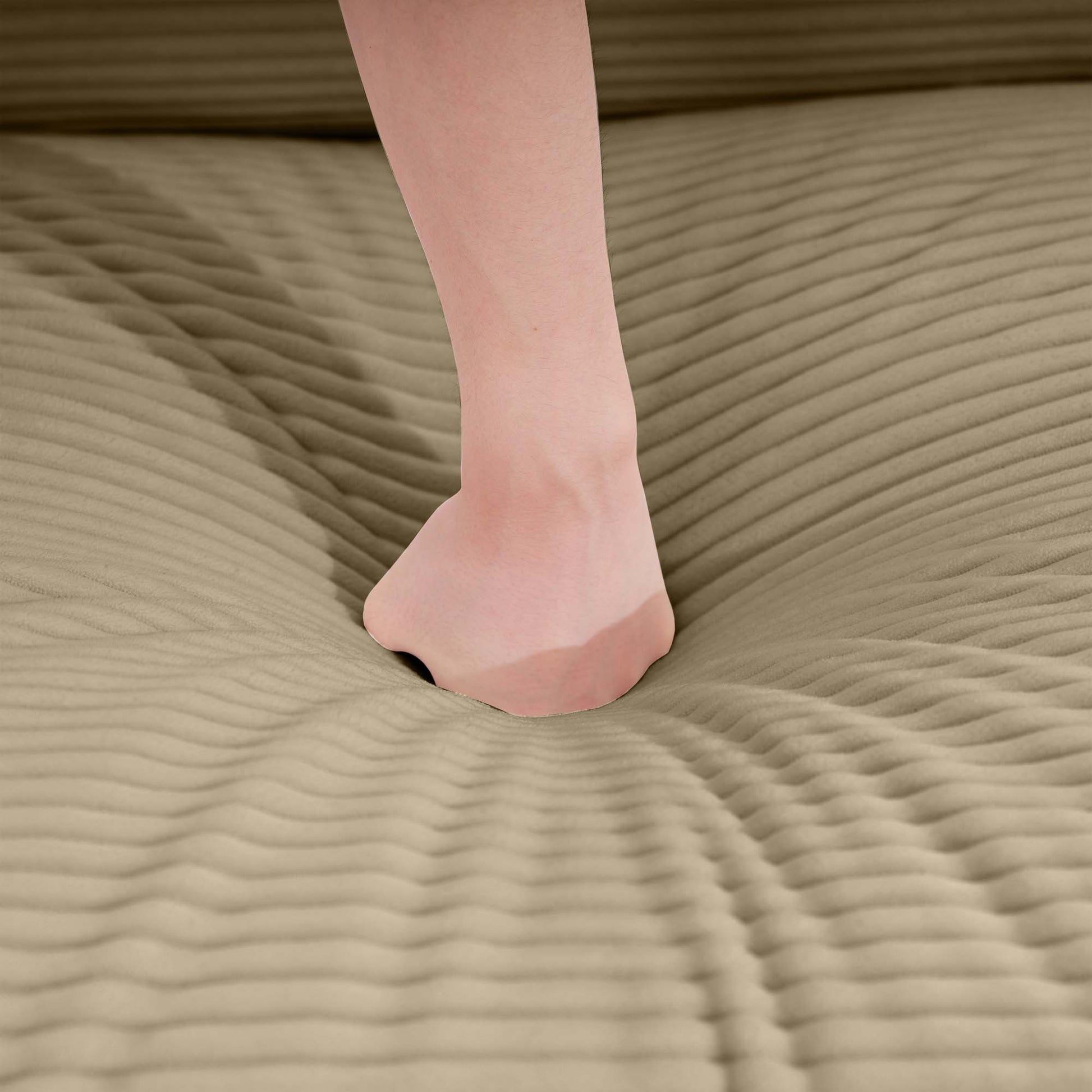 Closeup of a foot sinking into plush beige corduroy fabric demonstrating sofa comfort