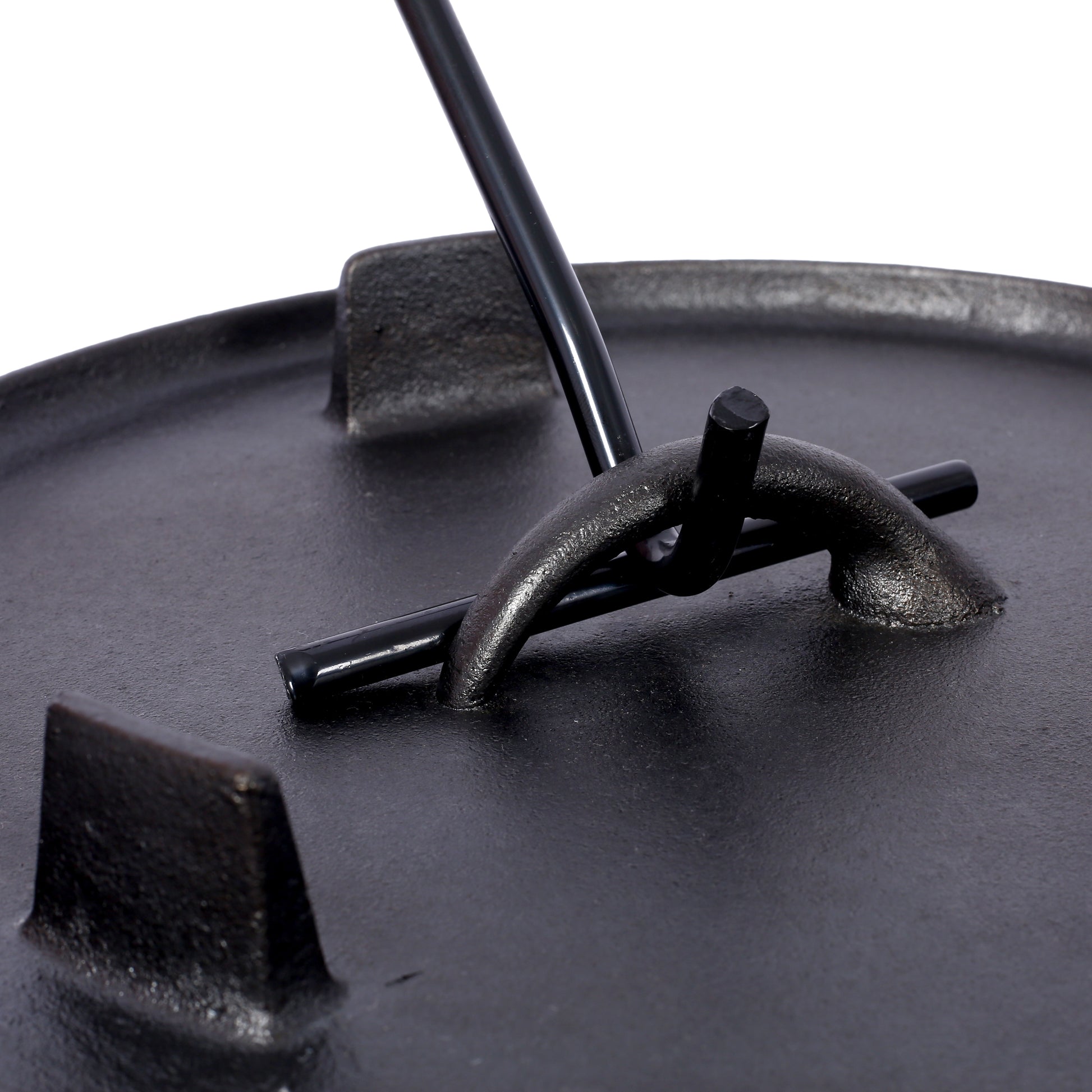 Closeup of a black cast iron Dutch oven lid with a black metal handle hook