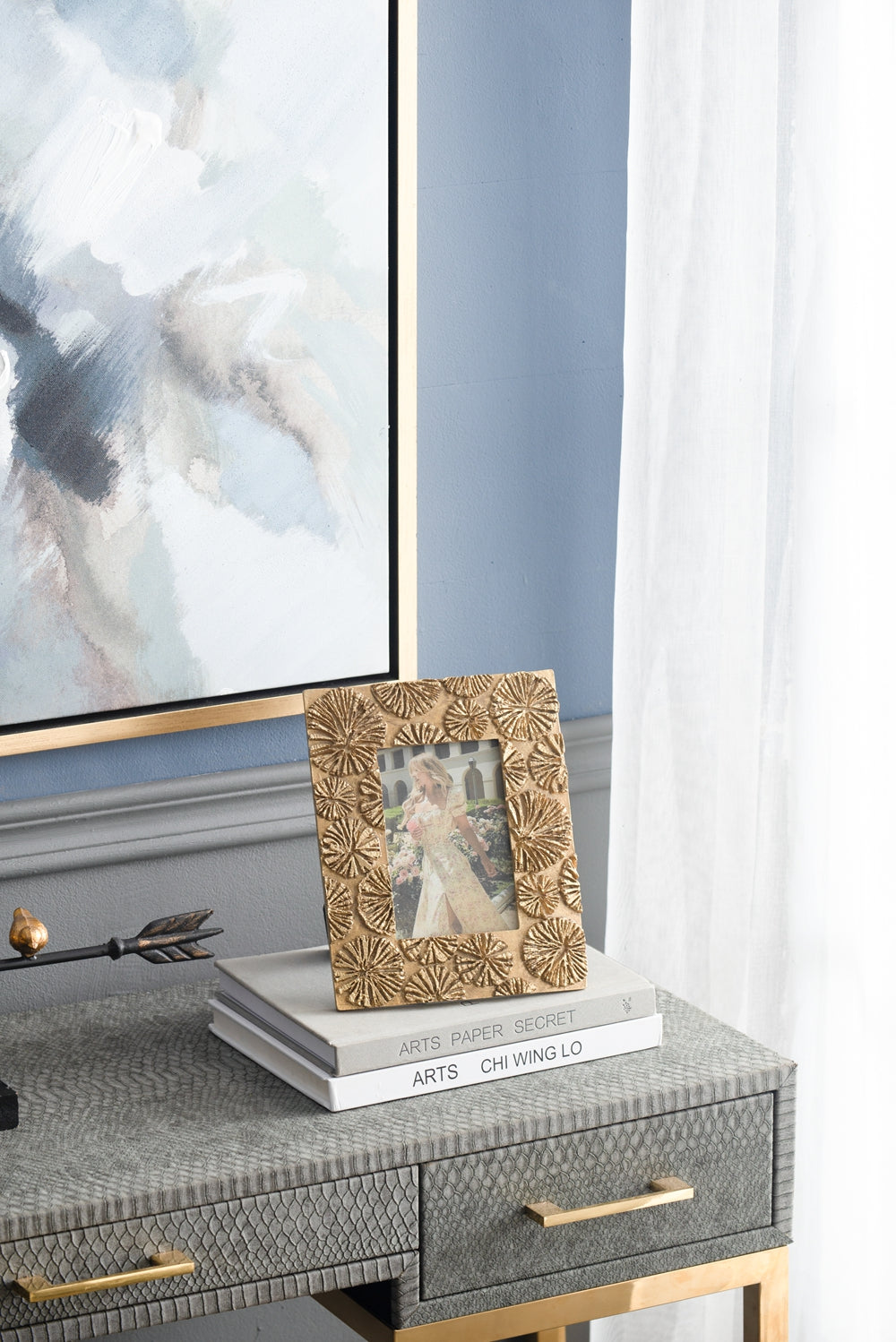 Gold ornate photo frame with raised floral design displaying a womans portrait