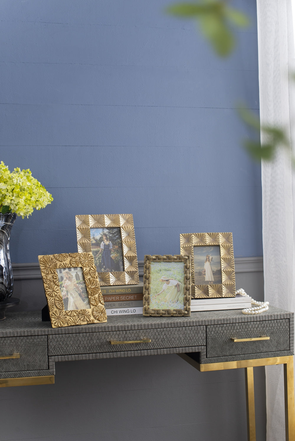 Gold embossed photo frame featuring a woman in a blue dress picking flowers