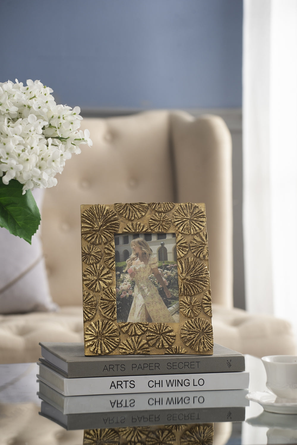 Textured gold picture frame with floral embellishments holding a photo of a woman in a yellow dress