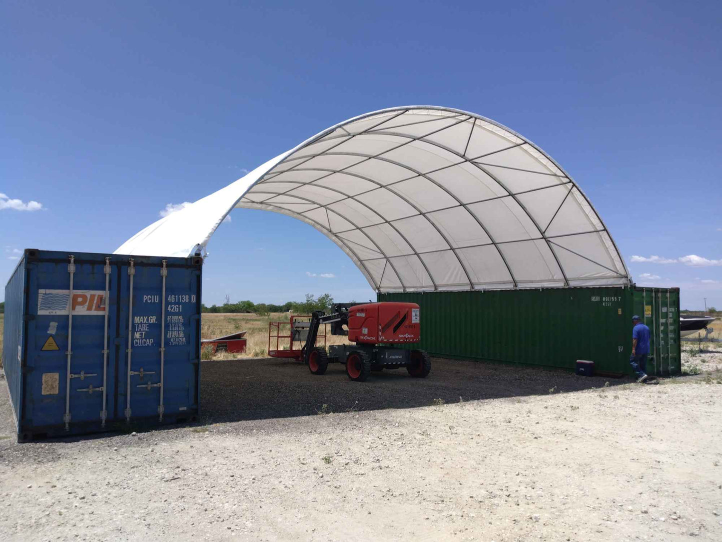 White arched fabric canopy supported by steel frame mounted on shipping containers