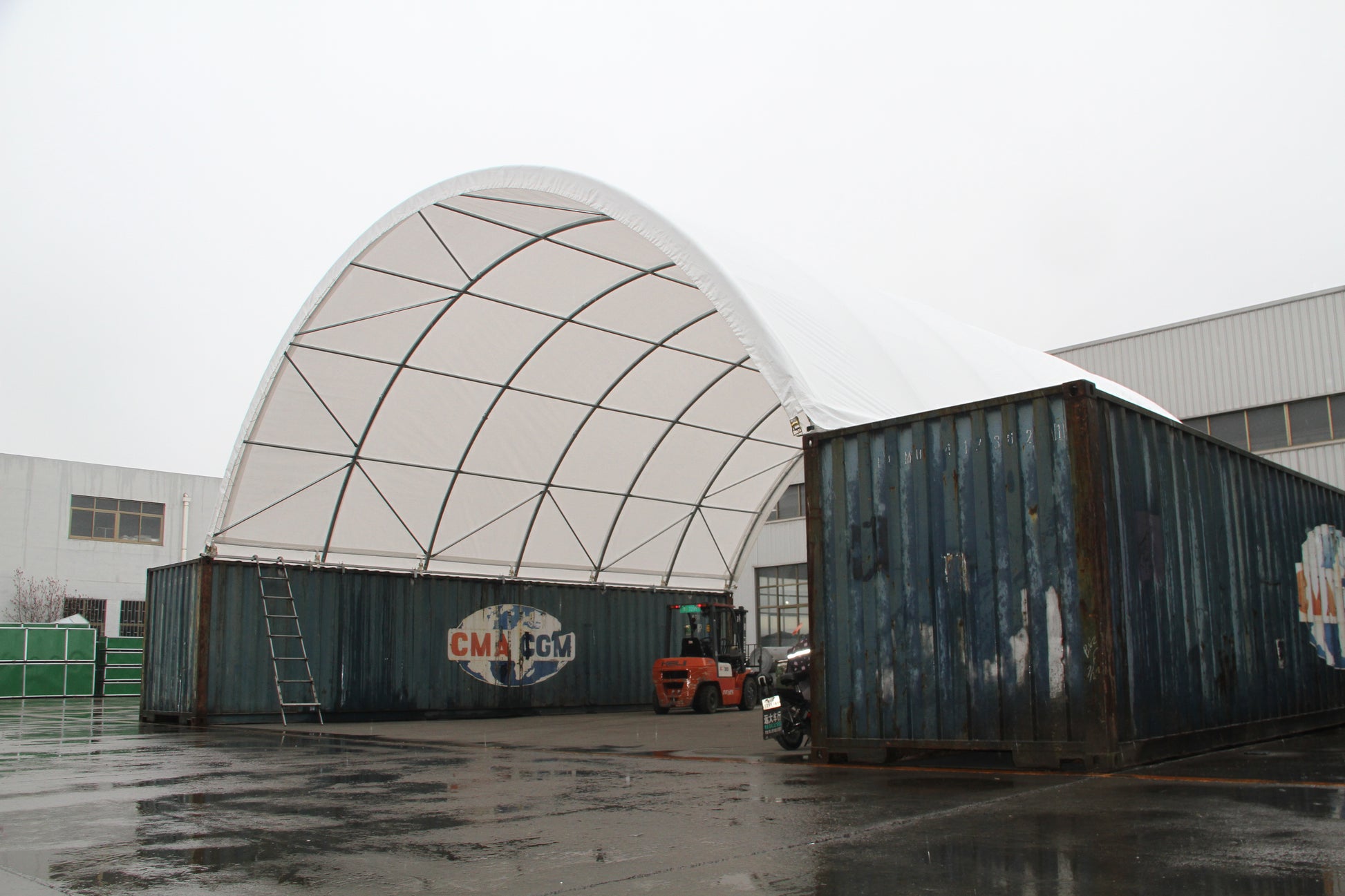 Large arched fabric structure supported by shipping containers a temporary warehouse solution