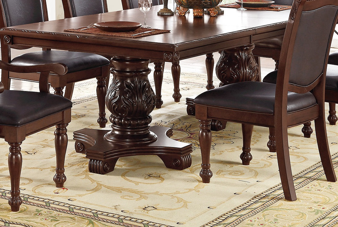 Ornate mahogany dining table with carved pedestal base and dark leather upholstered chairs
