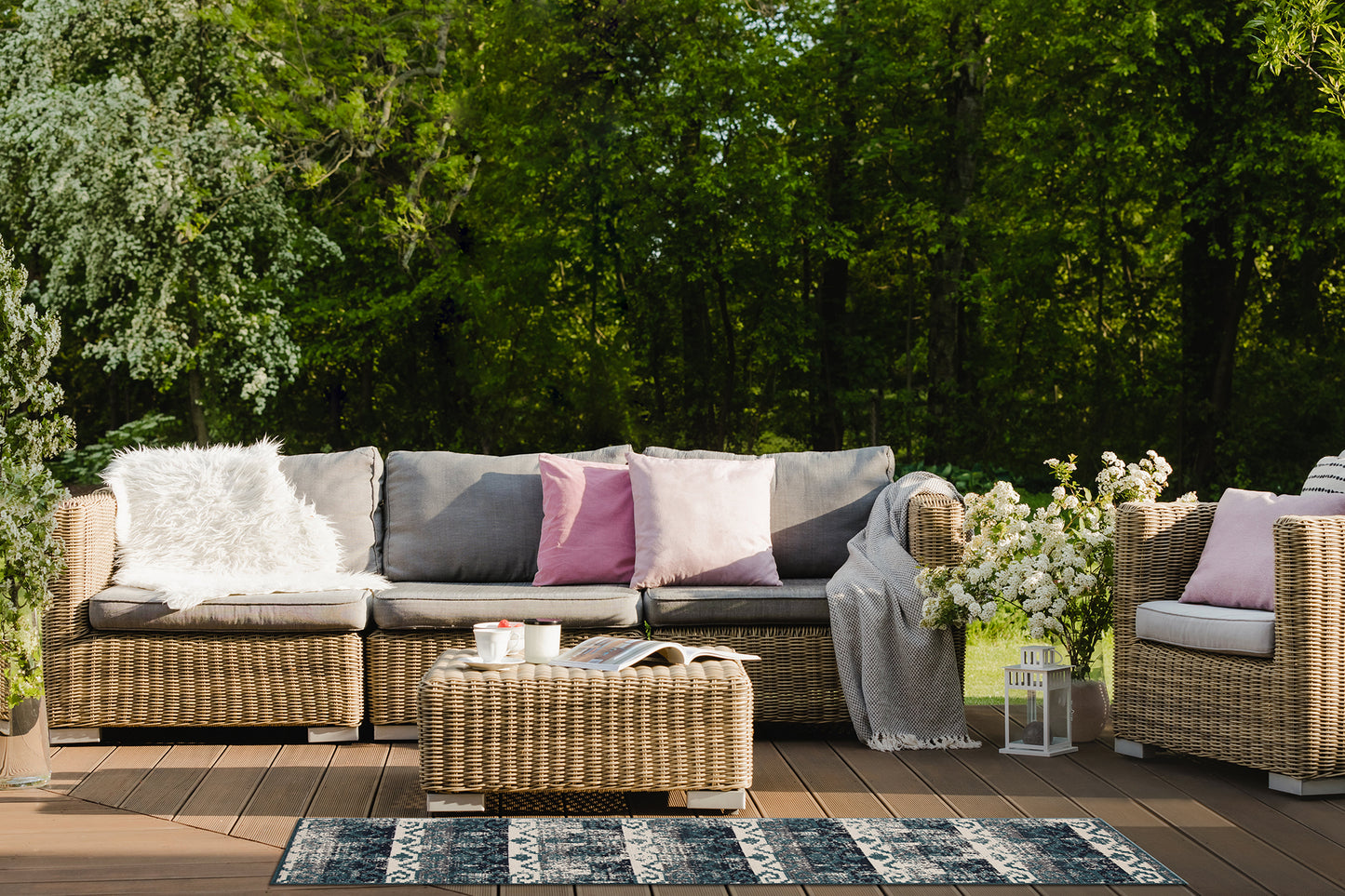 Woven rattan outdoor sofa with grey cushions and a faux fur throw pillow