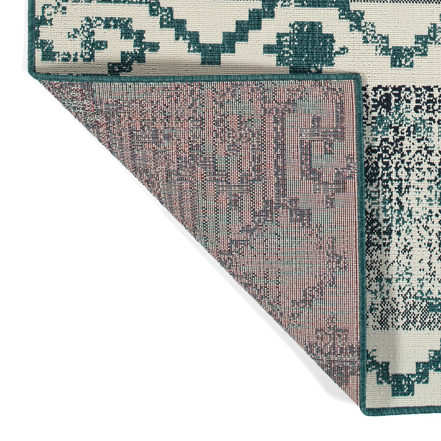 Reversible area rug with a cream and teal geometric design on one side and a distressed teal pattern on the other