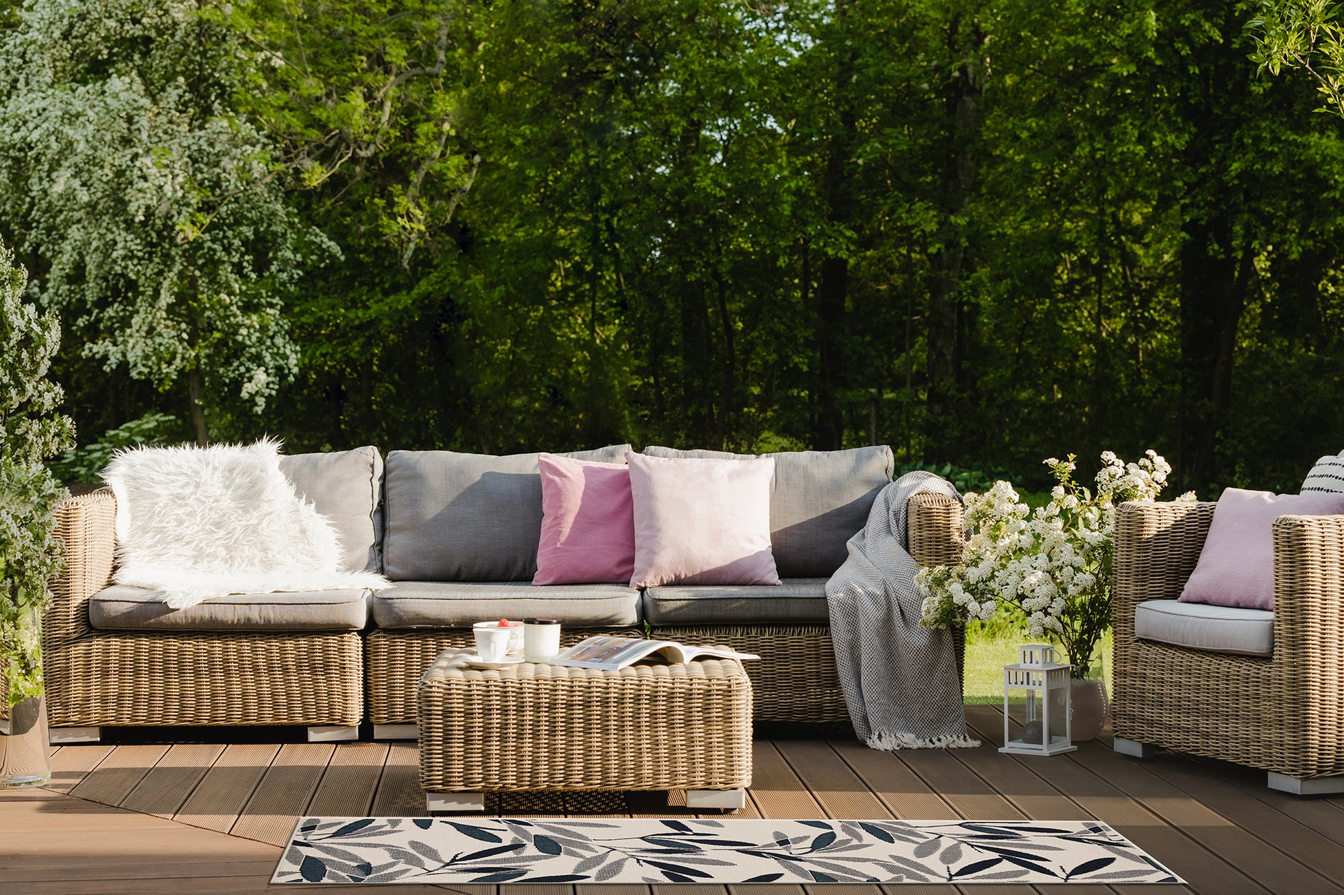Wicker outdoor sofa with plush grey cushions and white faux fur throw pillow