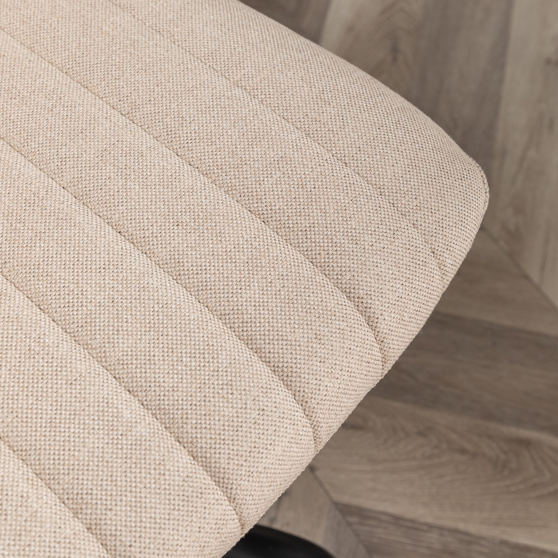 Closeup of textured beige fabric seat with horizontal stitching for modern furniture