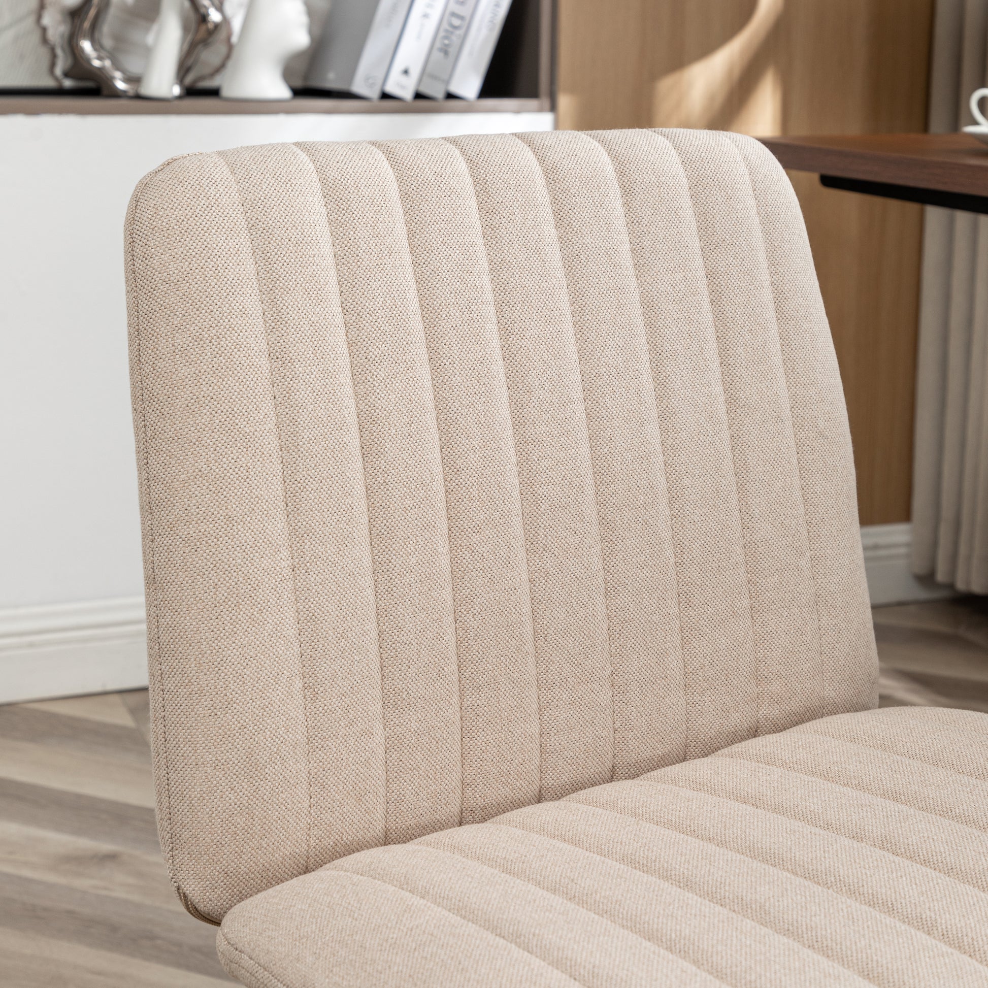 Closeup of a beige linen upholstered dining chair with vertical channel tufting