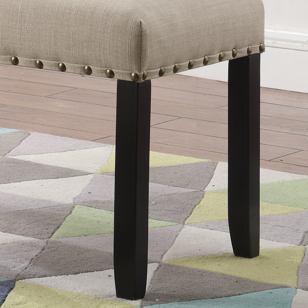Beige upholstered bench with nailhead trim and dark wood legs