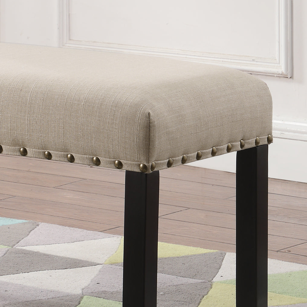 Beige linen upholstered bench with decorative brass nailhead trim