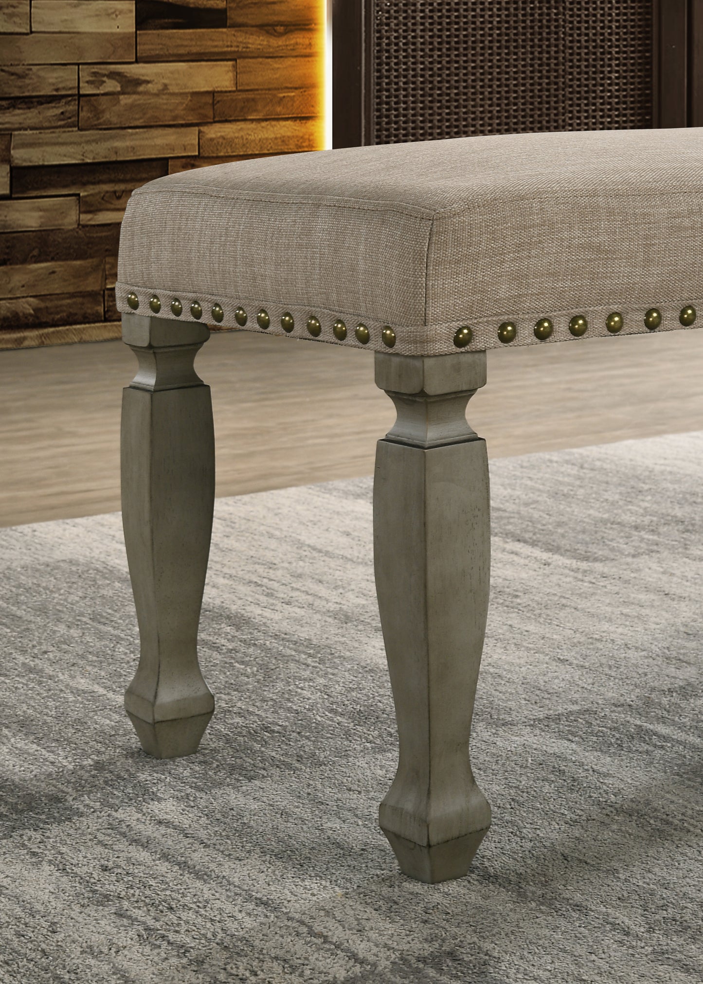 Taupe fabric bench with nailhead trim and distressed wood legs