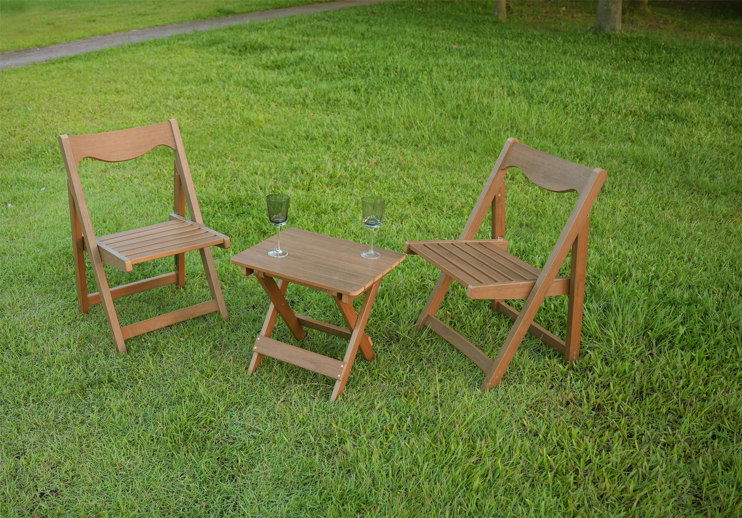 Two wooden folding chairs and a small wooden table set up on green grass perfect for outdoor relaxation