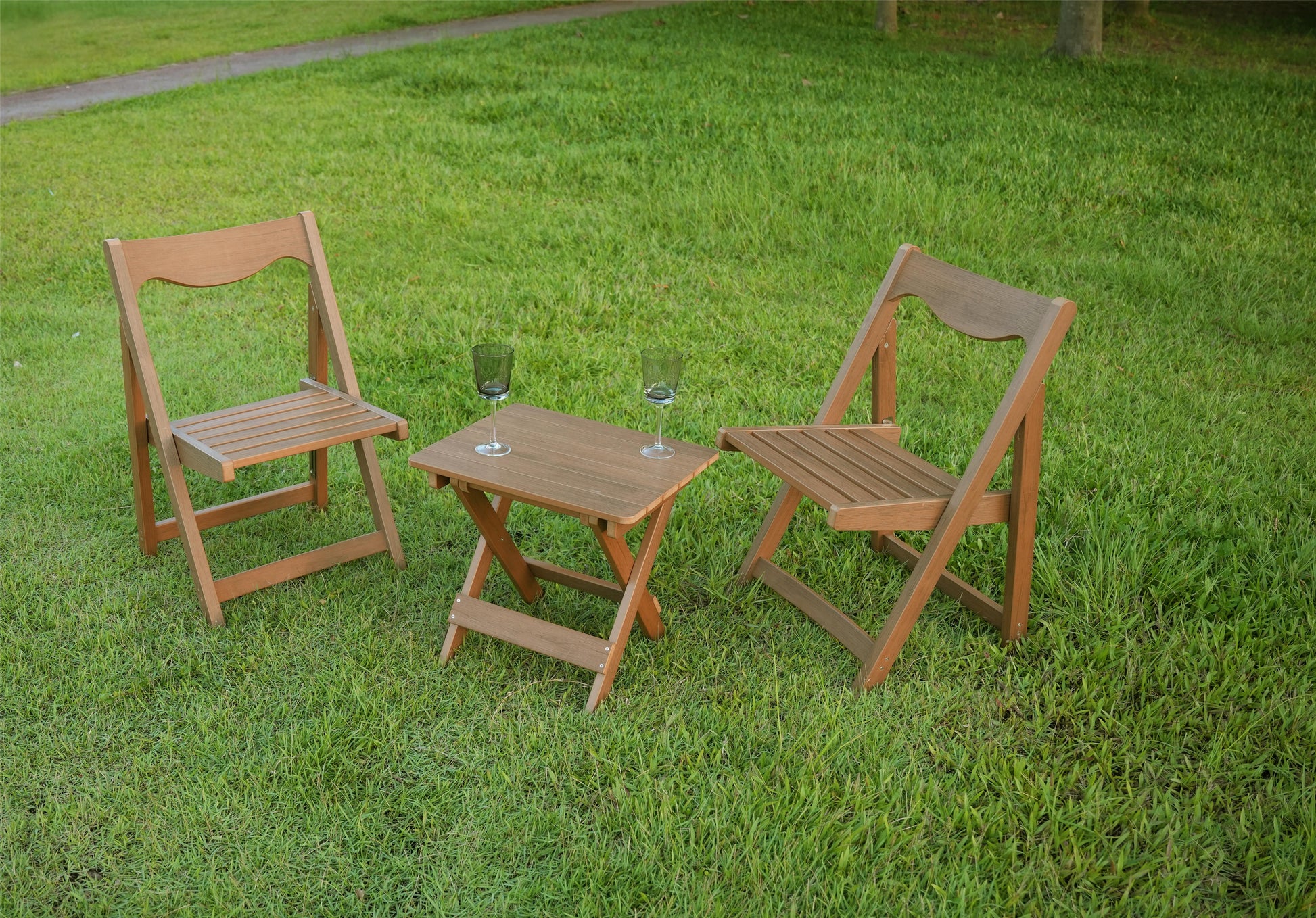 Two wooden folding chairs and a small wooden table set up on green grass perfect for outdoor relaxation