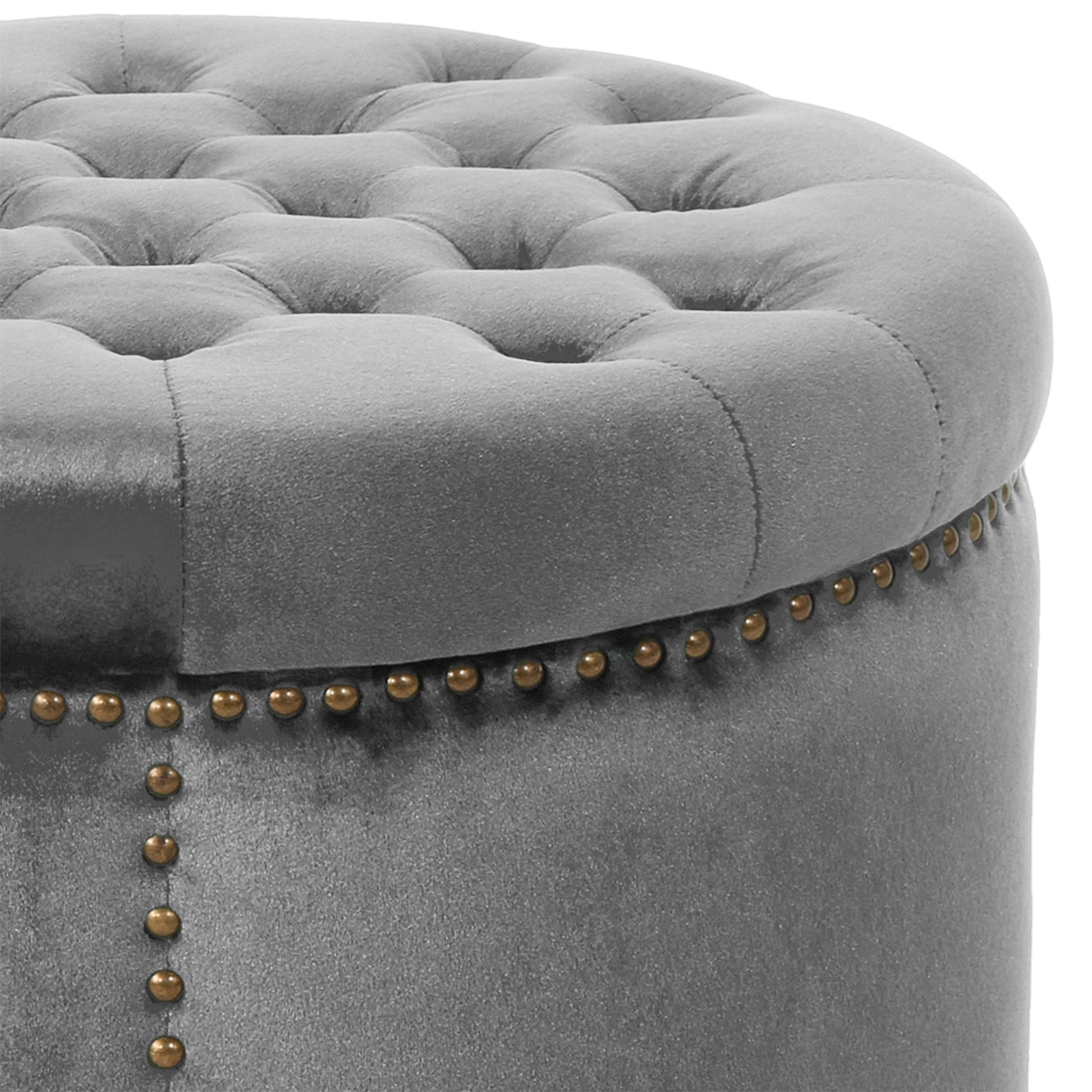 Tufted grey velvet ottoman with decorative brass nailhead trim and a plush round top