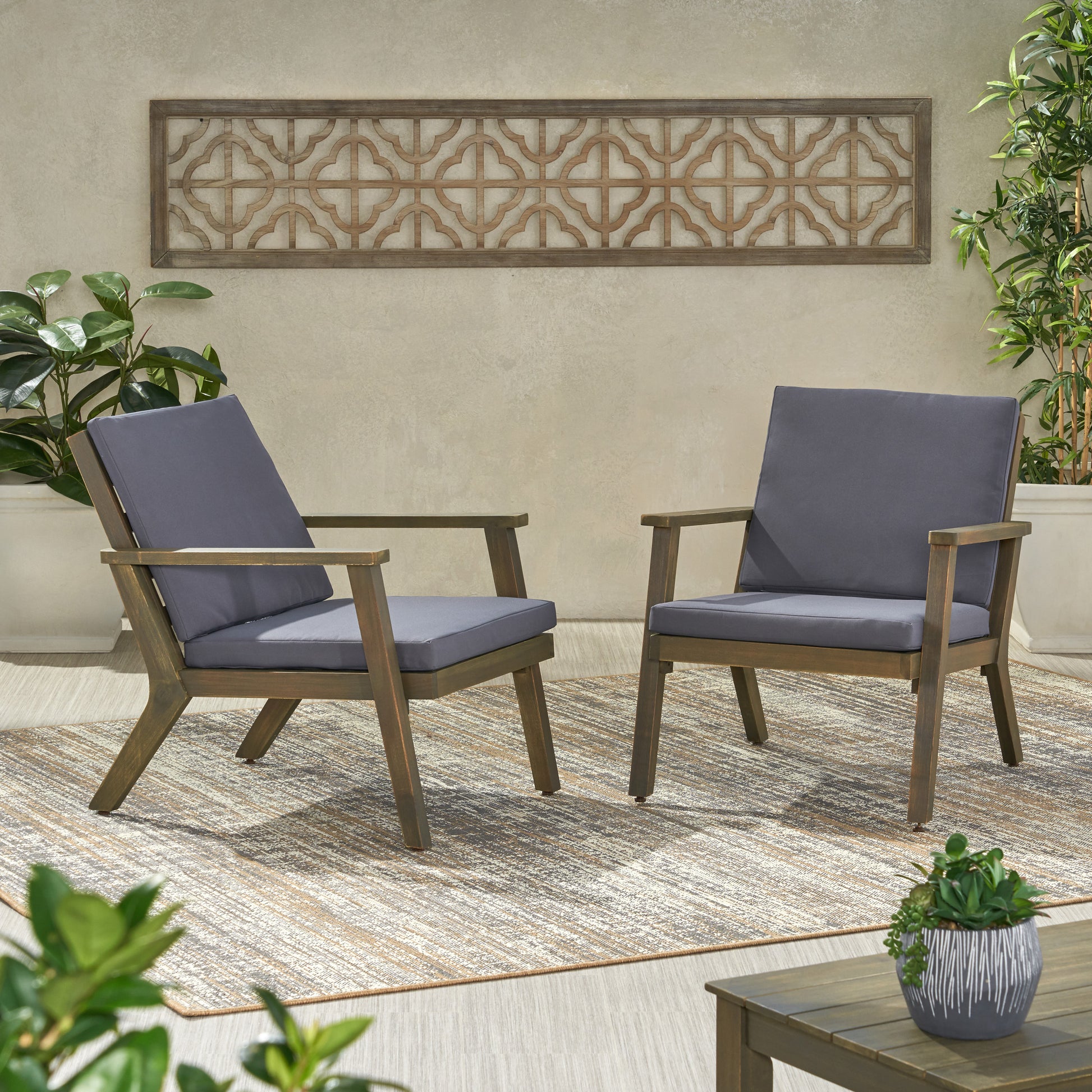 Two modern patio chairs with dark gray cushions on a patterned outdoor rug