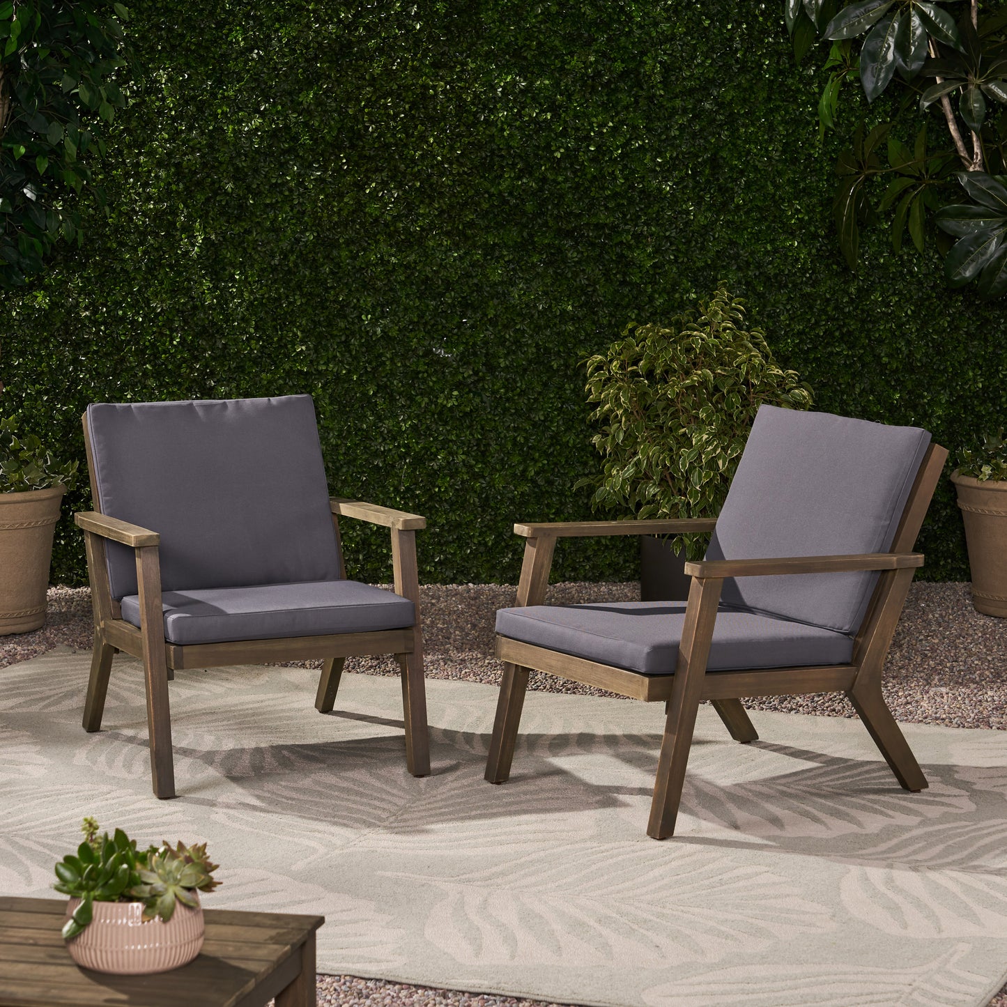 Two dark grey cushioned wooden patio chairs with armrests