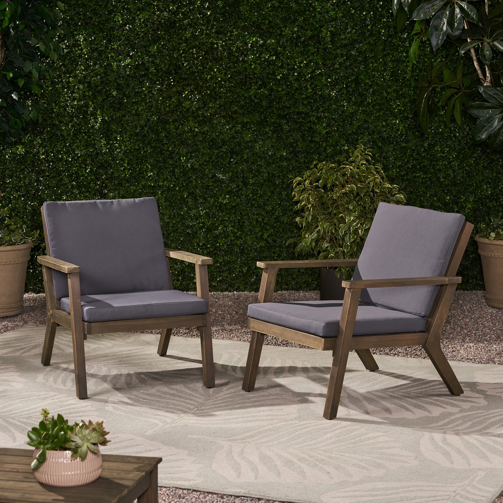 Two dark grey cushioned wooden patio chairs with armrests