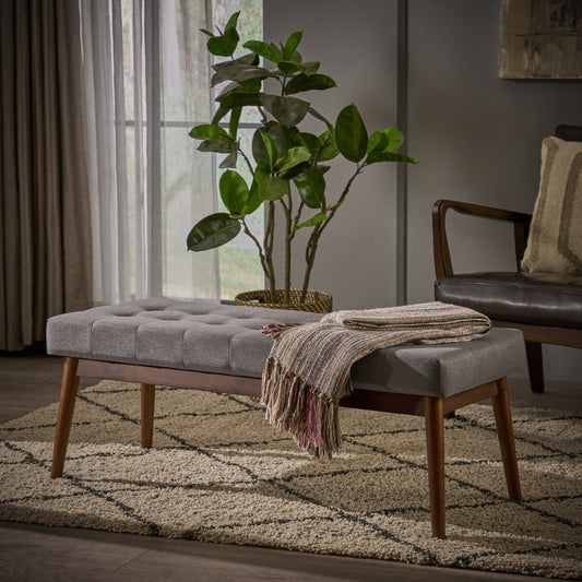 Tufted grey fabric ottoman with wooden legs and a woven throw for elegant entryway seating