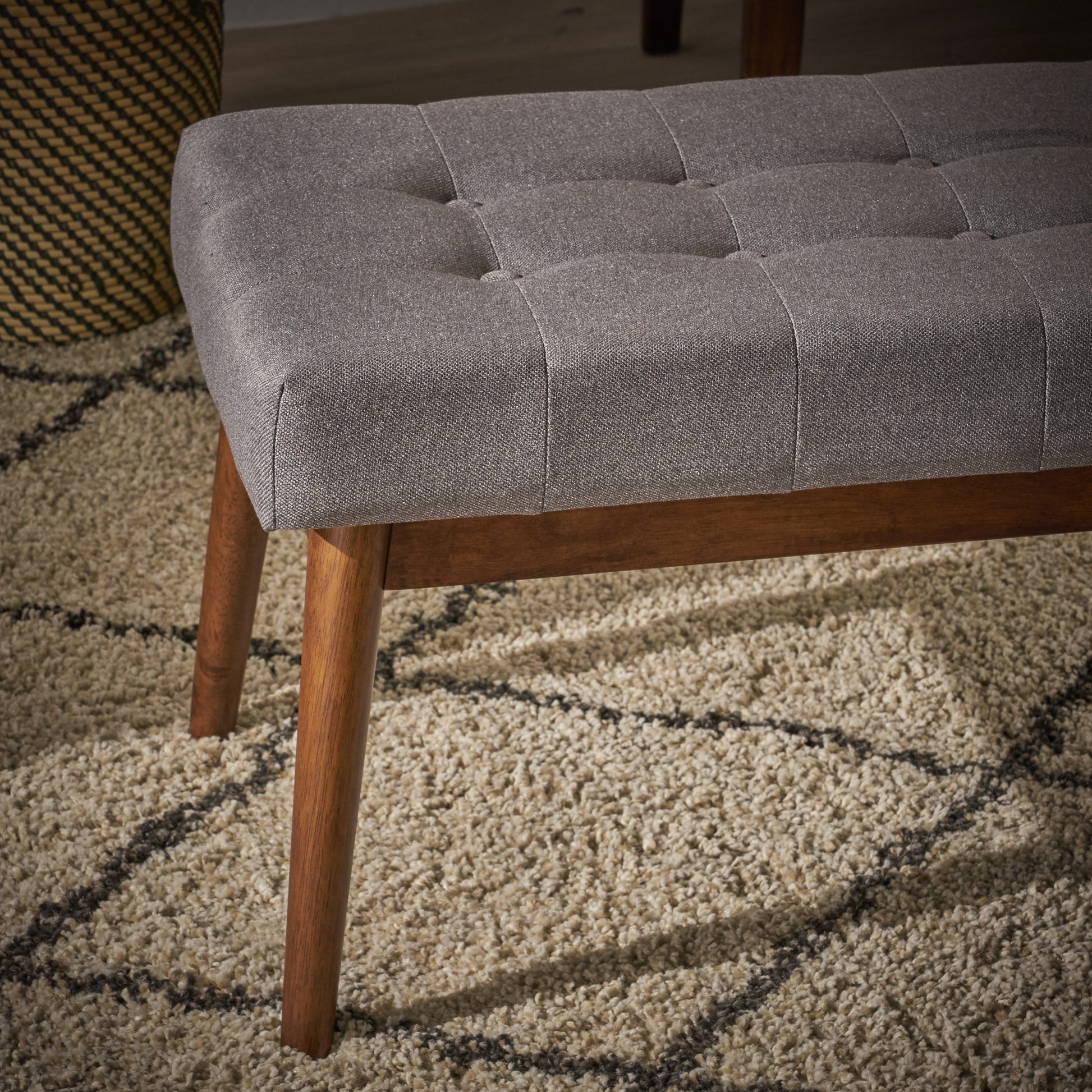 Tufted grey fabric bench with angled wood legs ideal for entryway seating