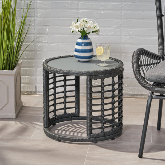 Gray rattan side table with glass top and blue striped vase with white flowers