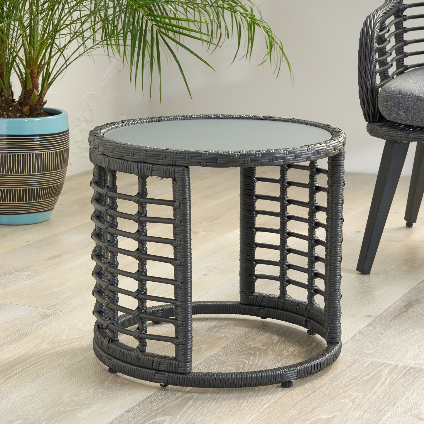 Dark gray wicker round side table with glass top on patio floor